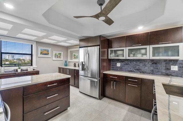 kitchen featuring a raised ceiling, tasteful backsplash, dark brown cabinets, and stainless steel fridge