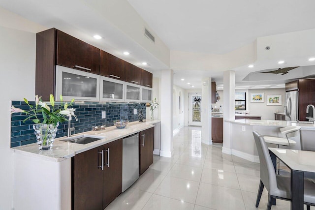 kitchen with sink, light tile patterned floors, stainless steel appliances, light stone counters, and tasteful backsplash