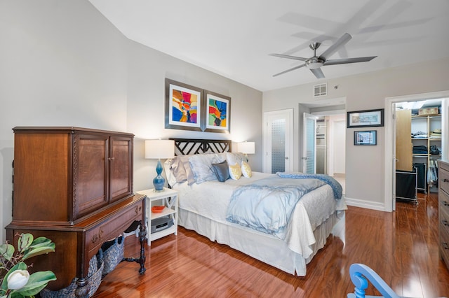 bedroom featuring hardwood / wood-style flooring, a walk in closet, ceiling fan, and a closet