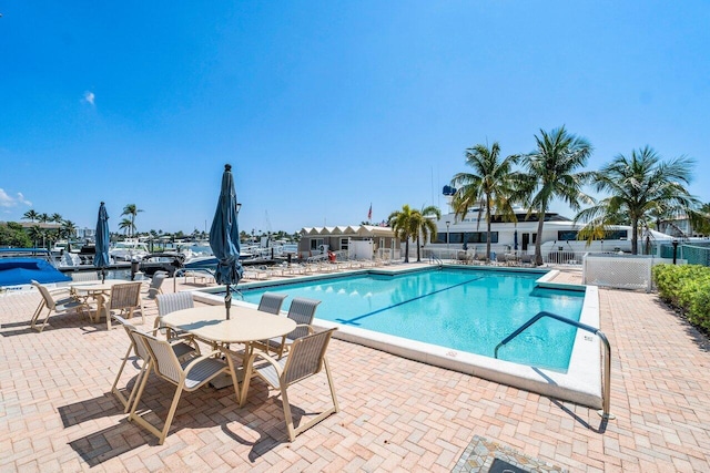 view of swimming pool with a water view and a patio area