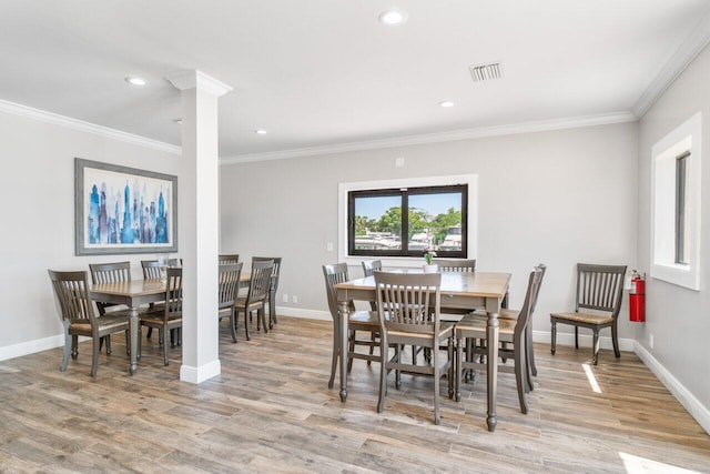 dining room featuring ornate columns, ornamental molding, and light hardwood / wood-style flooring