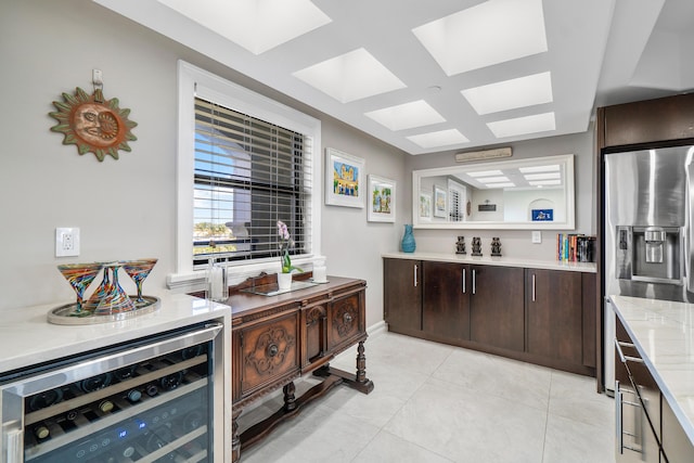 kitchen with stainless steel fridge, light tile patterned floors, beverage cooler, and dark brown cabinetry