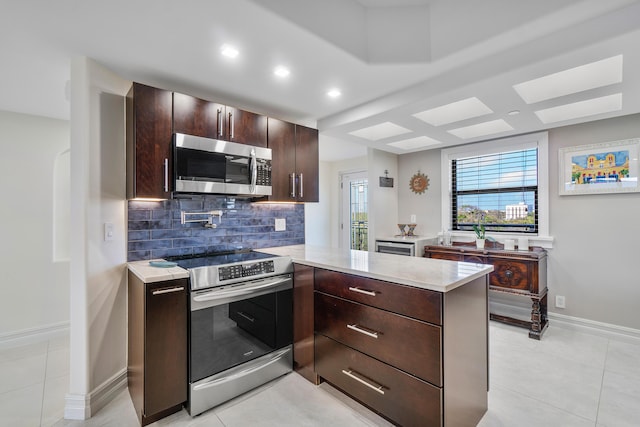 kitchen featuring light tile patterned floors, stainless steel appliances, tasteful backsplash, dark brown cabinetry, and kitchen peninsula