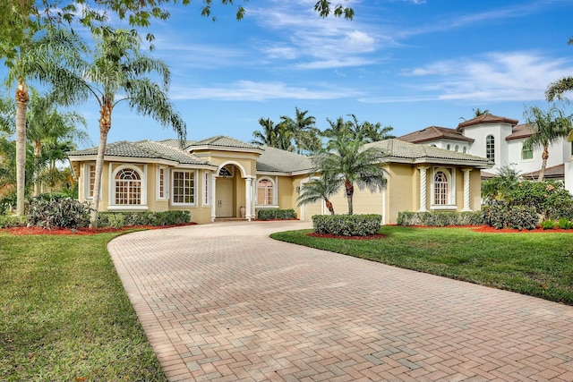 mediterranean / spanish-style home featuring a garage and a front yard