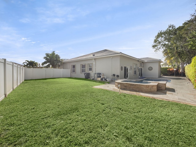 back of house with a pool with hot tub, a patio, and a lawn