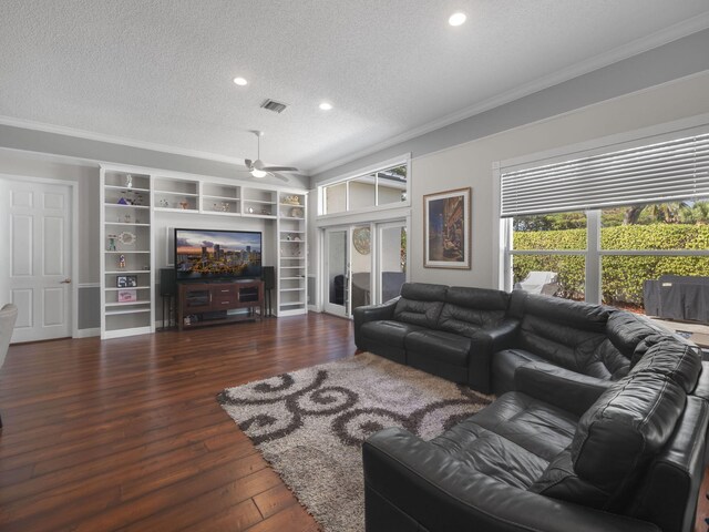 living room with ceiling fan, crown molding, dark wood-type flooring, and a textured ceiling