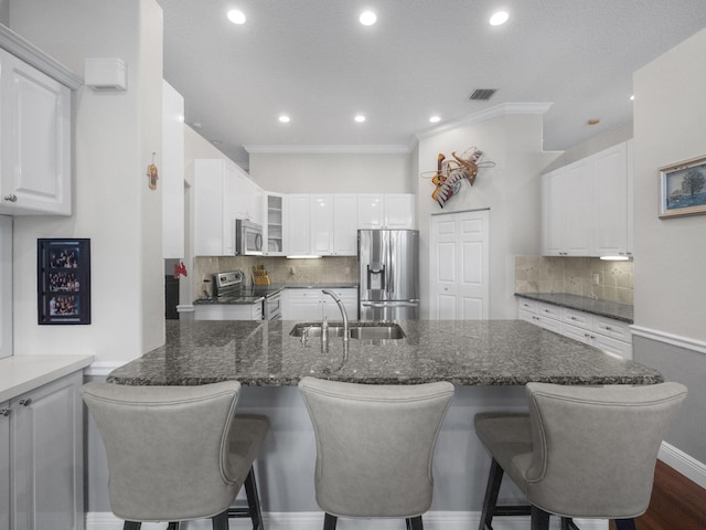 kitchen featuring appliances with stainless steel finishes, tasteful backsplash, white cabinets, sink, and dark stone counters