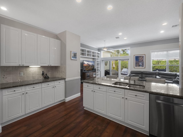 kitchen with sink, dark stone countertops, white cabinetry, and stainless steel dishwasher