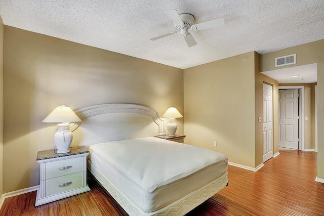 bedroom with a textured ceiling, ceiling fan, and hardwood / wood-style flooring