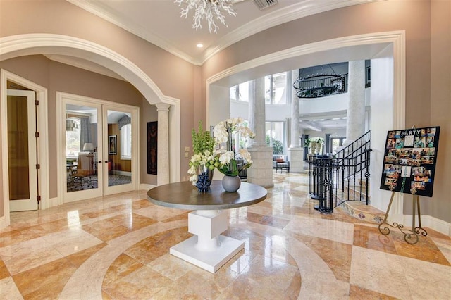 foyer with plenty of natural light, decorative columns, french doors, and ornamental molding