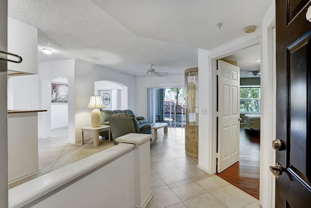 hall with a textured ceiling, plenty of natural light, and light tile patterned floors