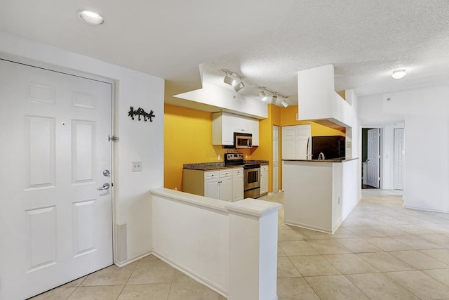 kitchen featuring appliances with stainless steel finishes, kitchen peninsula, a textured ceiling, white cabinets, and light tile patterned flooring