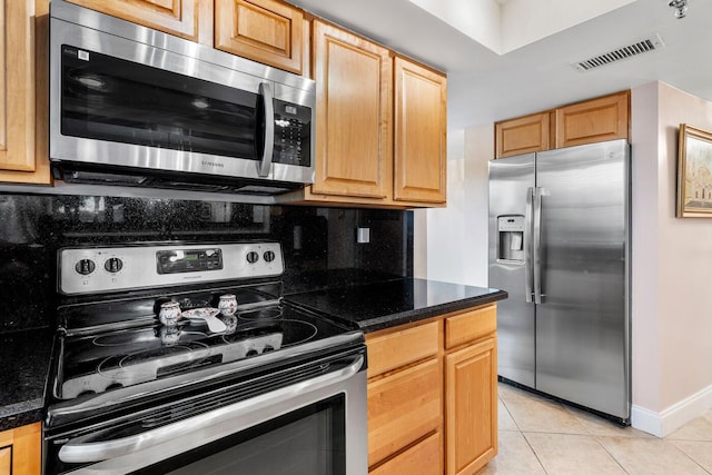 kitchen featuring light tile patterned floors, stainless steel appliances, tasteful backsplash, and dark stone counters