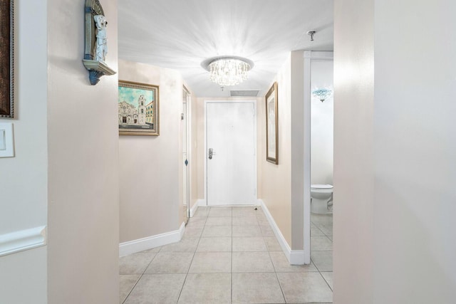 hall with light tile patterned flooring and a notable chandelier