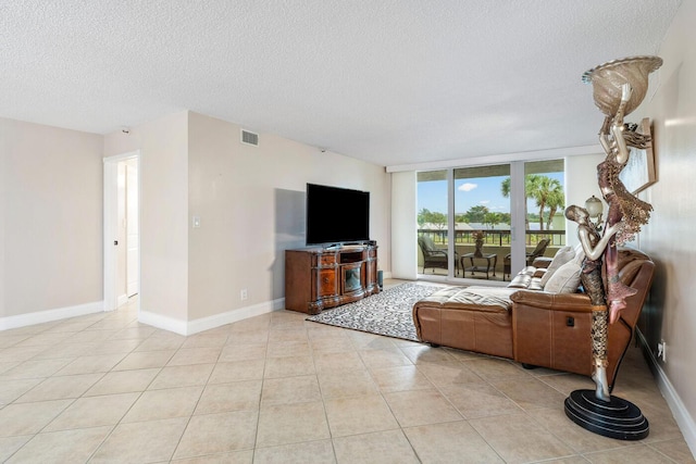 living room with a textured ceiling, light tile patterned floors, and expansive windows