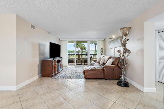 tiled living room featuring a textured ceiling and floor to ceiling windows