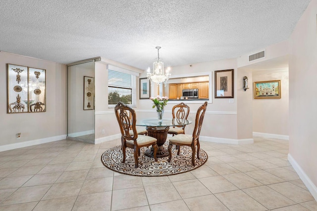 dining room featuring a textured ceiling, an inviting chandelier, and light tile patterned floors