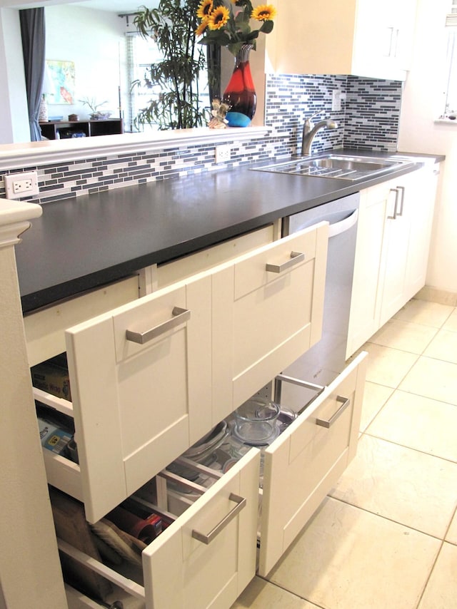 kitchen featuring white cabinets, light tile patterned flooring, decorative backsplash, and sink