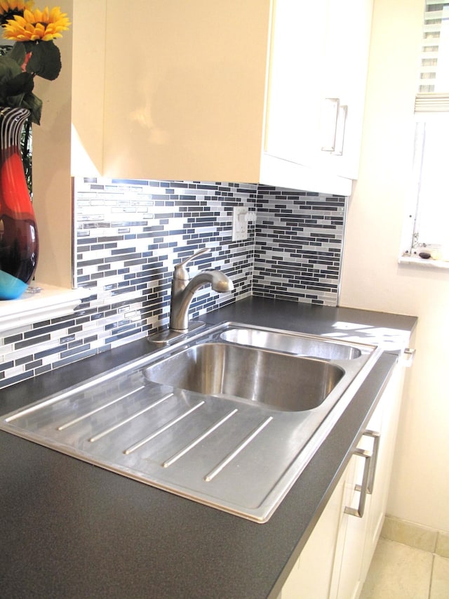 interior details with white cabinets, sink, and tasteful backsplash