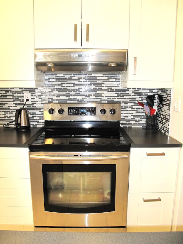 kitchen with white cabinets, stainless steel electric stove, and backsplash