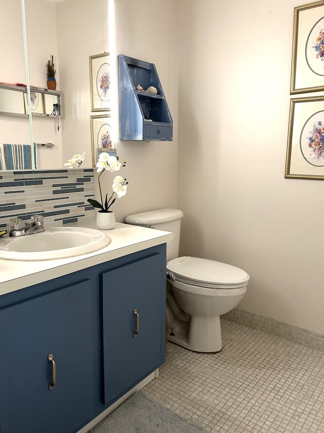 bathroom featuring toilet, tile patterned floors, vanity, and decorative backsplash