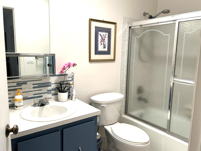 full bathroom featuring combined bath / shower with glass door, backsplash, vanity, and toilet