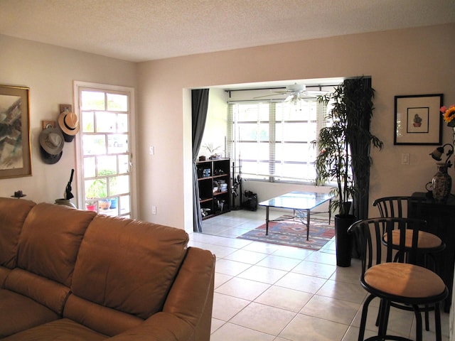 living room featuring a textured ceiling, ceiling fan, and light tile patterned flooring