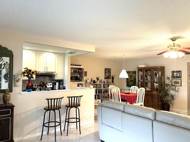 tiled living room with a textured ceiling and ceiling fan