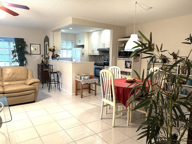 tiled dining space with a textured ceiling and ceiling fan