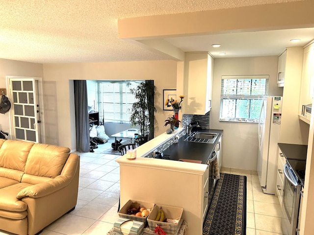 kitchen featuring electric stove, white fridge, light tile patterned floors, white cabinets, and sink