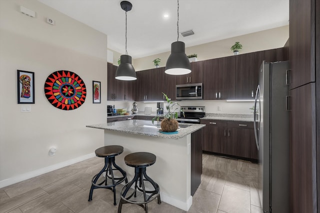 kitchen with light stone counters, hanging light fixtures, stainless steel appliances, a kitchen island, and a breakfast bar area