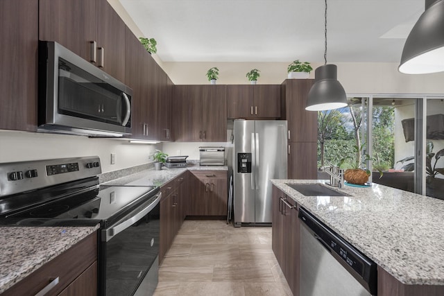 kitchen with stainless steel appliances, light stone countertops, pendant lighting, sink, and dark brown cabinets