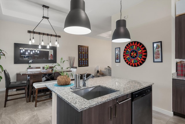 kitchen featuring light stone countertops, dark brown cabinetry, sink, decorative light fixtures, and stainless steel dishwasher