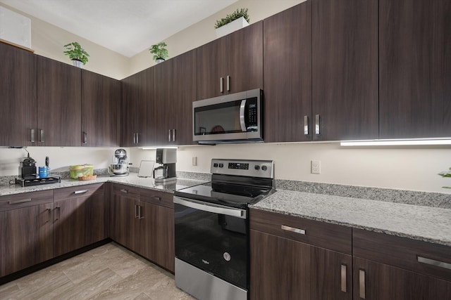 kitchen featuring stainless steel appliances, dark brown cabinetry, and light stone countertops