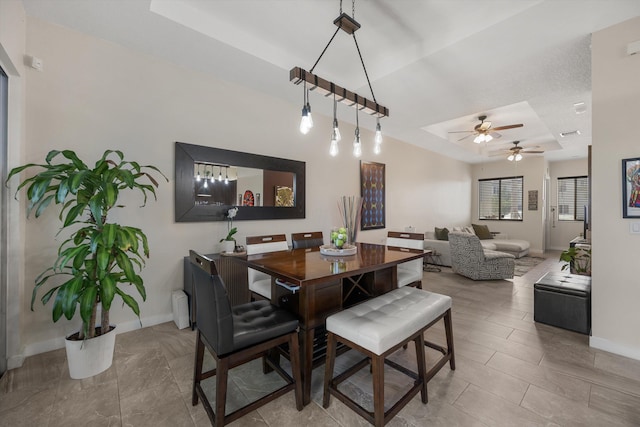 dining area featuring ceiling fan and a tray ceiling