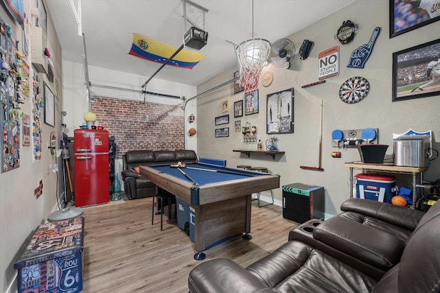 game room featuring pool table, brick wall, and light wood-type flooring