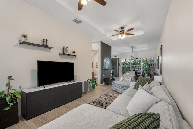 living room featuring a raised ceiling and ceiling fan