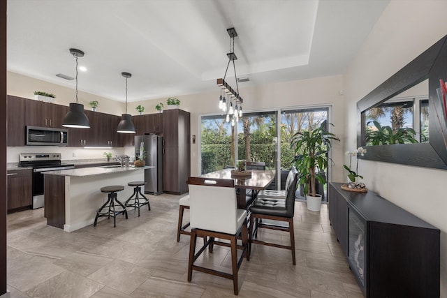 dining space featuring a raised ceiling and sink