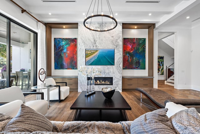 living room featuring beam ceiling, a large fireplace, a chandelier, and light wood-type flooring