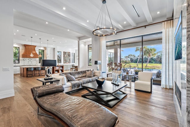 living room with beamed ceiling, a chandelier, and light hardwood / wood-style floors