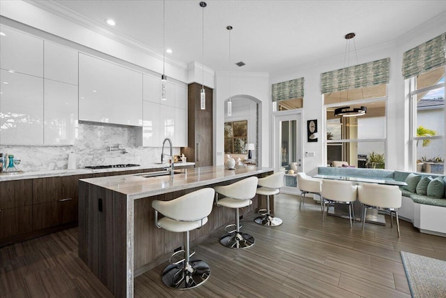 kitchen featuring sink, a breakfast bar area, white cabinetry, pendant lighting, and backsplash