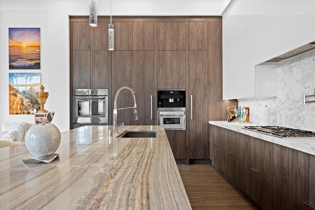 kitchen with decorative light fixtures, sink, decorative backsplash, light stone counters, and stainless steel appliances