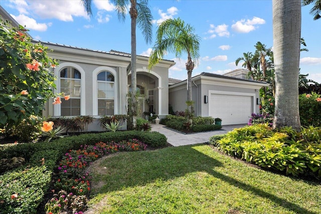 mediterranean / spanish home featuring a front yard and a garage