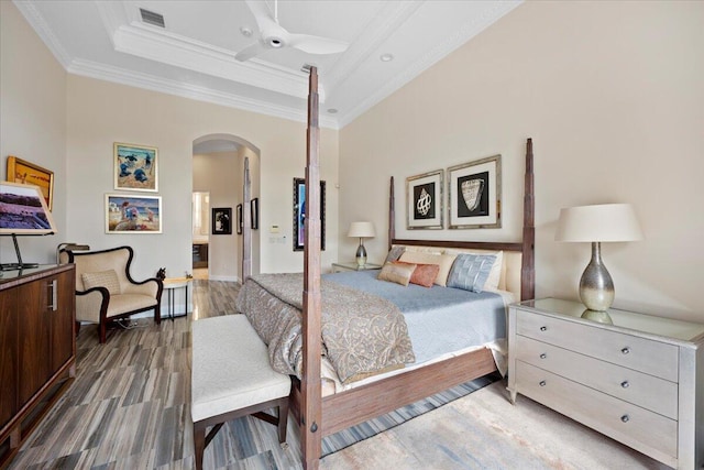 bedroom with ceiling fan, ornamental molding, a raised ceiling, and wood-type flooring