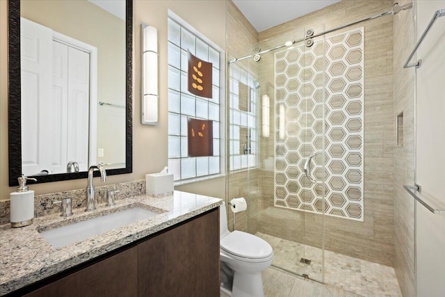 bathroom featuring vanity, a tile shower, and toilet