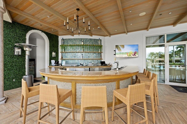 bar with an inviting chandelier, wood ceiling, parquet flooring, and beamed ceiling