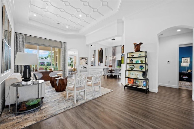 living room with crown molding, a tray ceiling, dark hardwood / wood-style floors, and a high ceiling