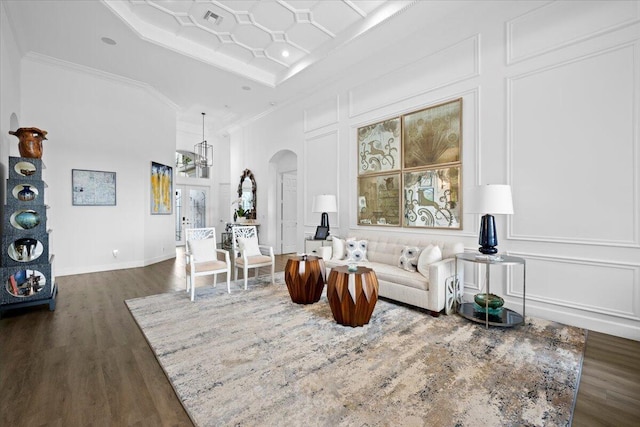 living room with dark hardwood / wood-style flooring, coffered ceiling, ornamental molding, and french doors