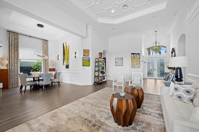 living room with crown molding, dark hardwood / wood-style floors, french doors, and a chandelier