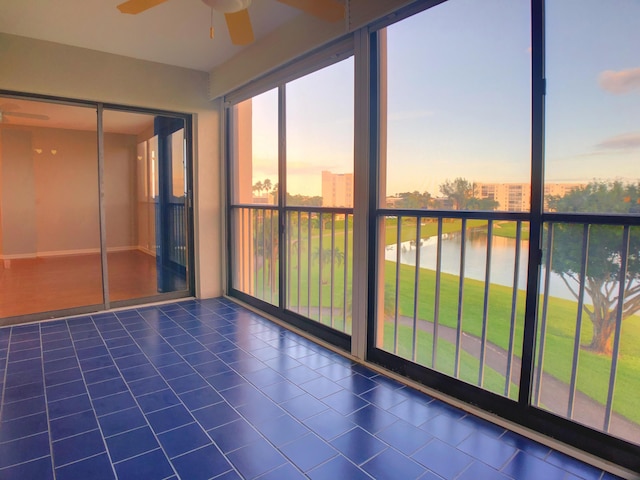 unfurnished sunroom featuring a water view and ceiling fan